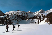 An AAI group skiing into the Rock Creek drainage with Bear Creek Spire behind.