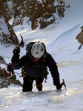 A climber making quality ice axe placements while leading on steep alpine ice
