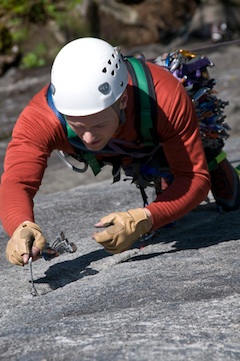 An aid climber carefully places his next piece while climbing at Index.