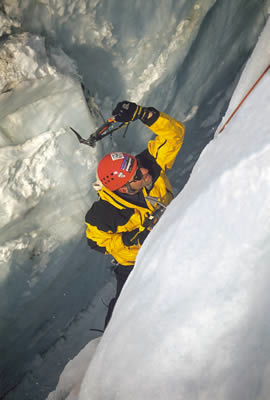 A climber works on ice climbing technique by climbing out of a crevasse.