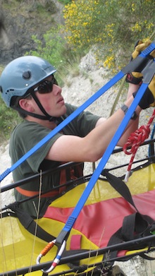 SAR - A litter attendant hangs on a litter during a technical lower.