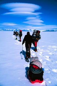 Snowshoeing on the ice cap with lenticular clouds, an indicator of high winds, above.
