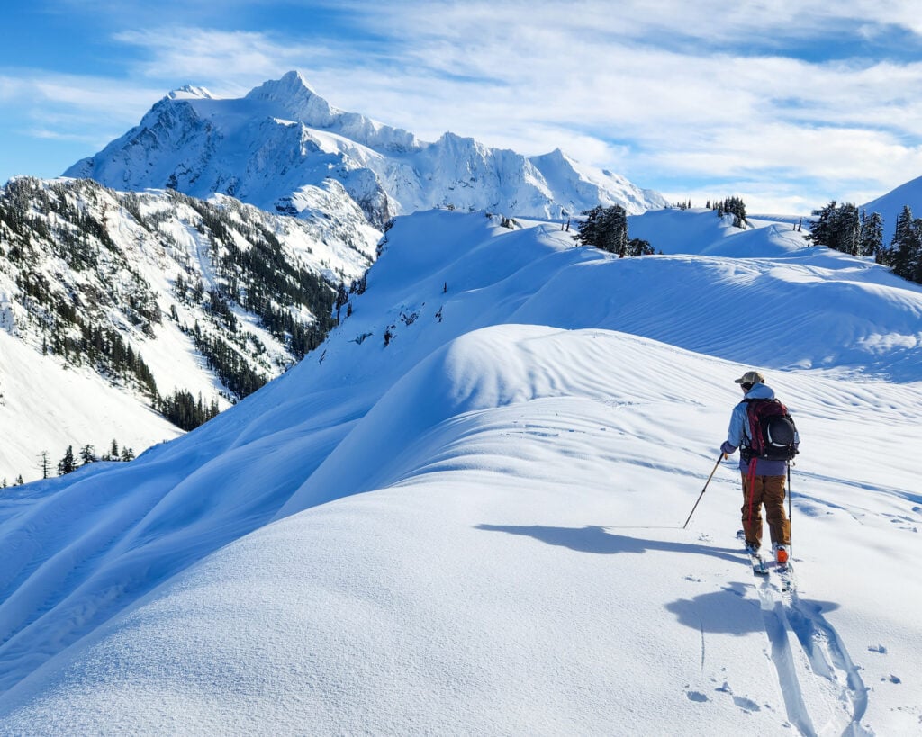 A backcountry skier sets their up track in the Baker backcountry with Shuksan in the background