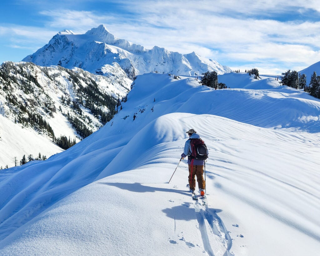 A skier sets their uphill skin track while touring in the Baker backcountry during an Alpine Institute course with Shuksan in the background