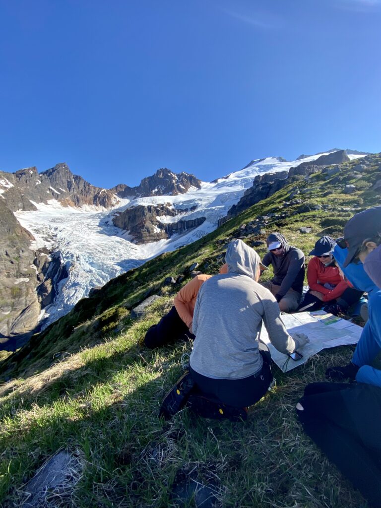 A group of people study a map in the mountains, making a plan for their route.