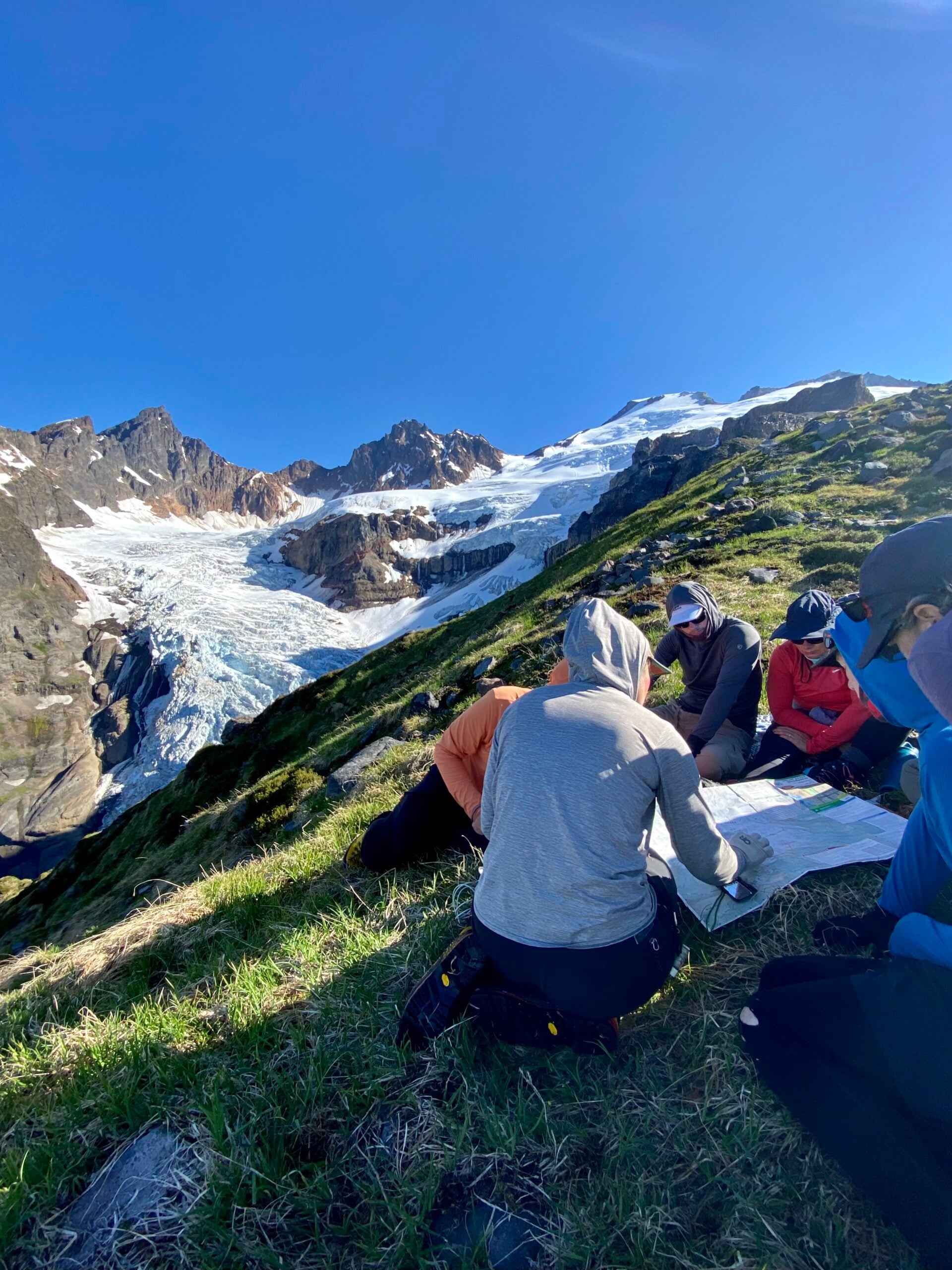 dispatch-card-bg A group of people study a map in the mountains, making a plan for their route.