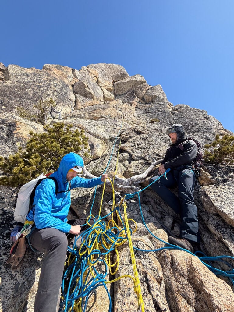 Climbing students mind a belay anchor in an Alpinism 2 course