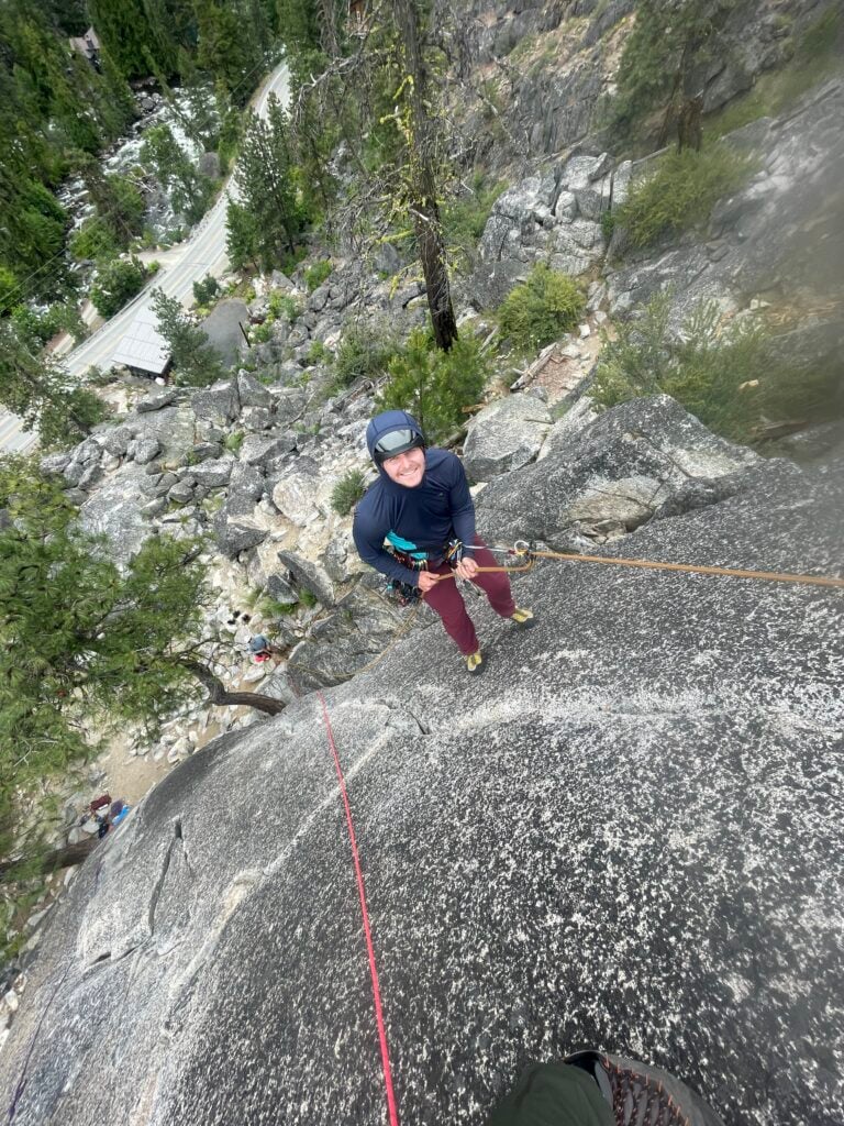 A climber smiles as they climb above a glacier river in Leavenworth, WA