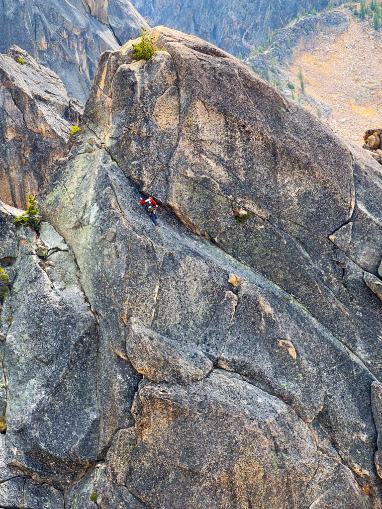 A climber dwarfed by the size of the climb on Concord Tower in Washington Pass on an American Alpine Institute rock climbing program