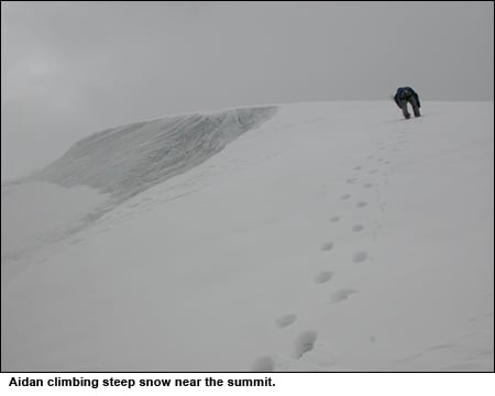 Aiden leading up steep snow below the summit of Reddomaine