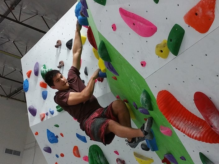 A climber bouldering on an indoor climbing wall