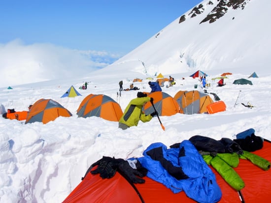 Drying gear in the sun at Camp 2 with a cloudy Kahiltna Pass below.