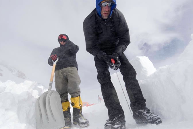 Erik Johnson and Coley Gentzel cut snow blocks for camp walls in high winds at 14,200'. Photo: Matthew Anderson