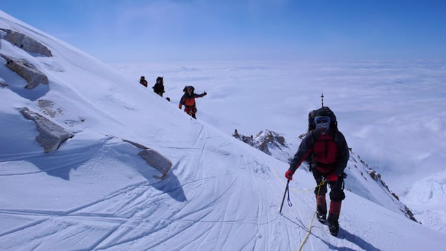 An AAI team rounds the corner to High Camp with the ridge in the background.