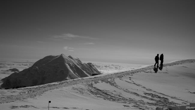 Climbers walk along the edge of the plateau near High Camp with Mount Foraker behind.