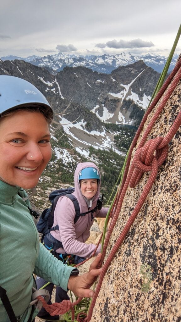 Happy rock climbers at the belay anchor doing a North Cascades alpine rock multi-pitch climb with the American Alpine Institute