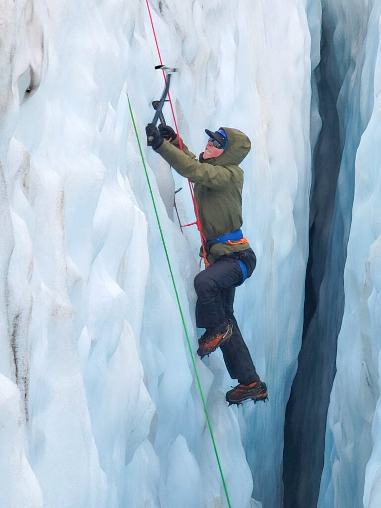 A student in the recess of a serac learning how to alpine ice climb on the Coleman glacier of Mt. Baker in Washington