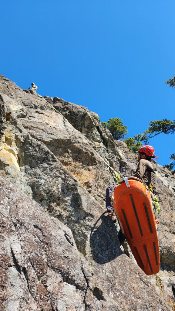 Students work with a litter on a cliff edge on an American Alpine Institute rope rescue program