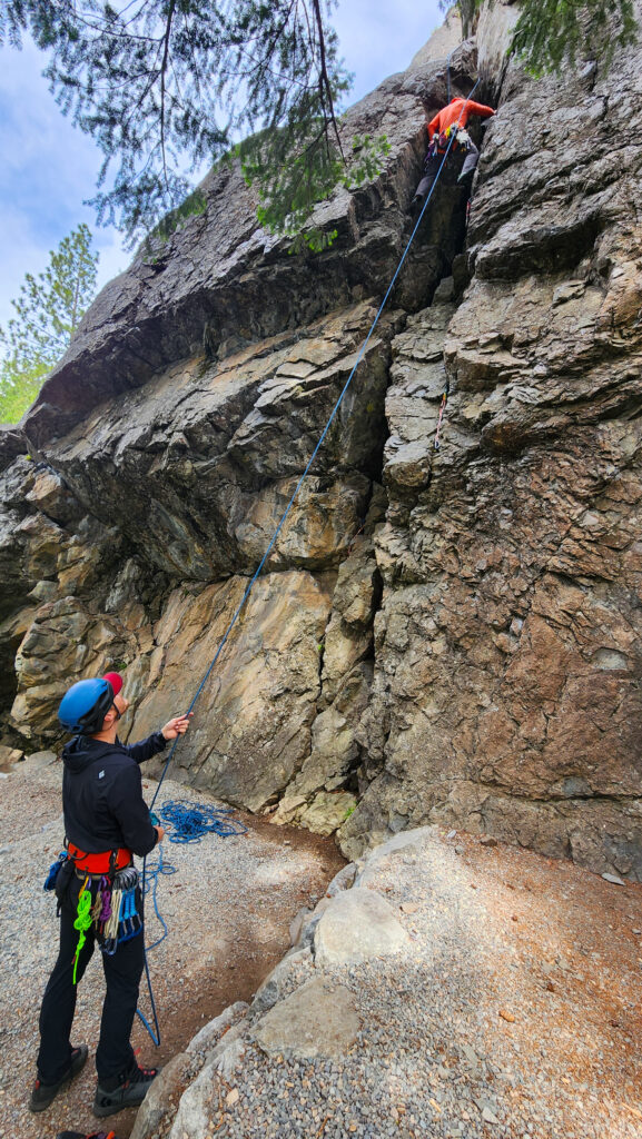 Climbers work on climbing a top-roped route. One climber belays as the other makes their way to the top of the route on an American Alpine Institute rock climbing course