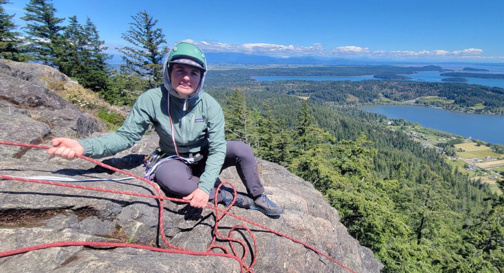 A climber belays their partner from the top anchor of a climb at scenic Mt. Erie in Washington on an American Alpine Institute rock climbing course.