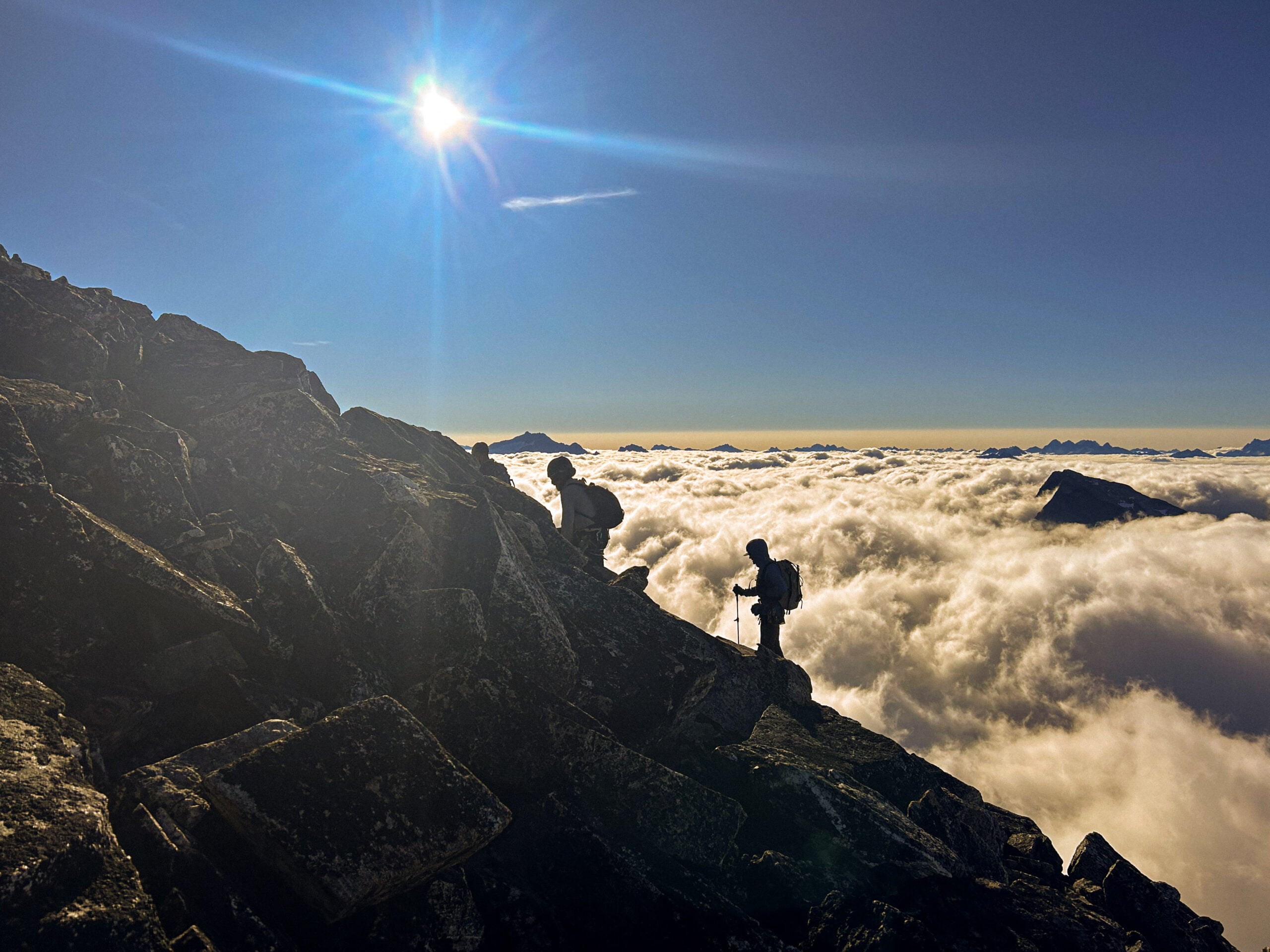 Climbers silhouetted in the clouds while they climb in the remote alpine wilderness of the North Cascades during American Alpine Institute Alpine Mountaineering and Technical Leadership Part 4 (AMTL4)
