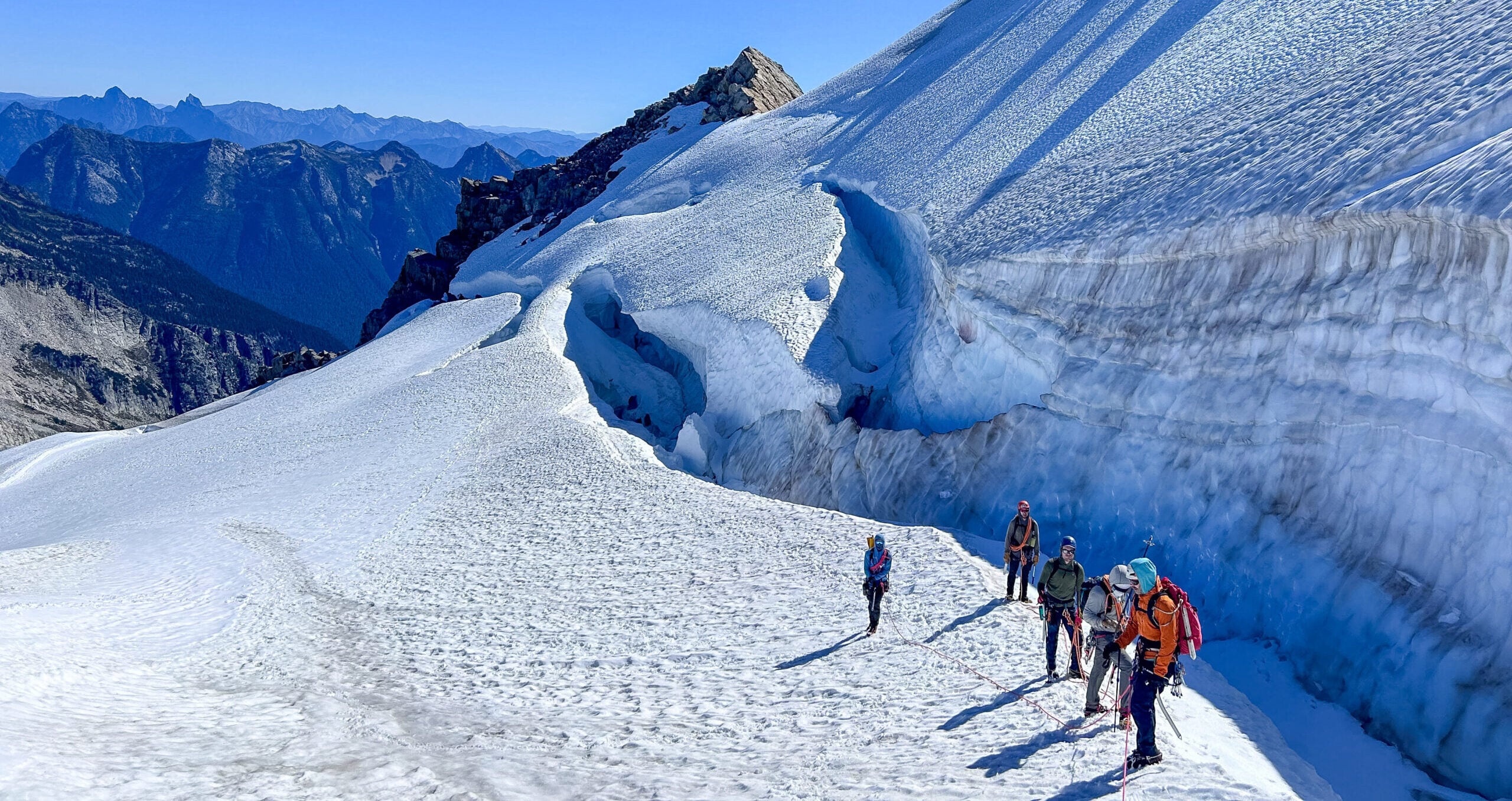 A team of climbers contemplate how to cross a bergschrund in the remote alpine wilderness of the North Cascades during American Alpine Institute Alpine Mountaineering and Technical Leadership Part 4 (AMTL4)