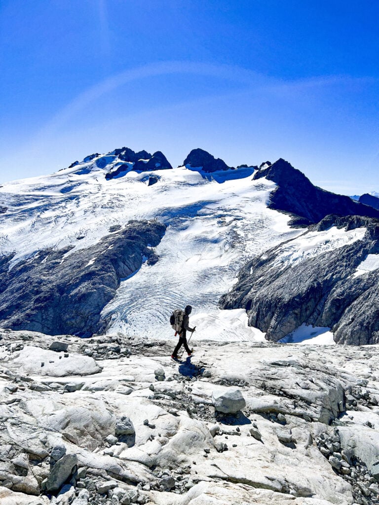 A person treks across a rock section during their expedition in the remote alpine wilderness of the North Cascades during American Alpine Institute Alpine Mountaineering and Technical Leadership Part 4 (AMTL4)