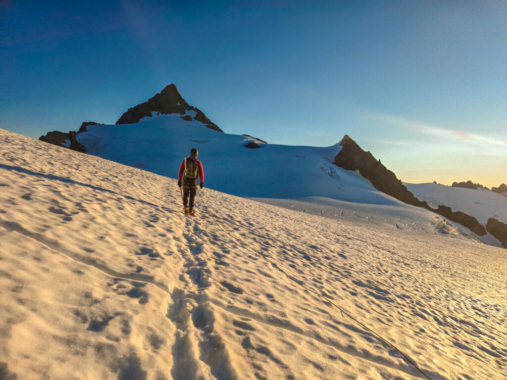 A climber chases sunrise to the summit pyramid of Mt. Shuksan via the Sulphide Glacier during an American Alpine Institute mountaineering program