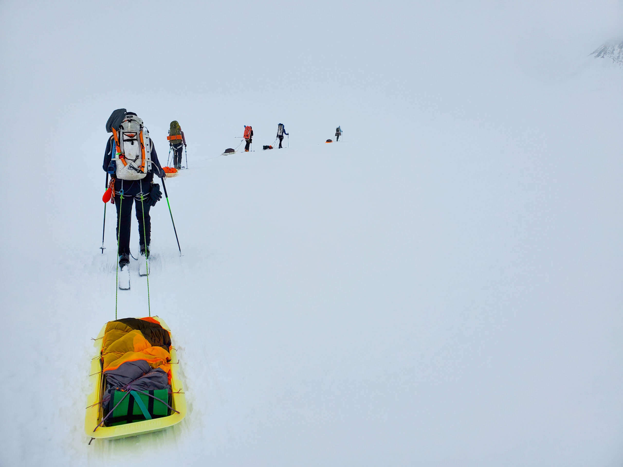 Learning how to navigate in white out conditions is essential when mountaineering, especially when carrying sleds on skis like this group of backcountry tourers on an American Alpine Institute ski course