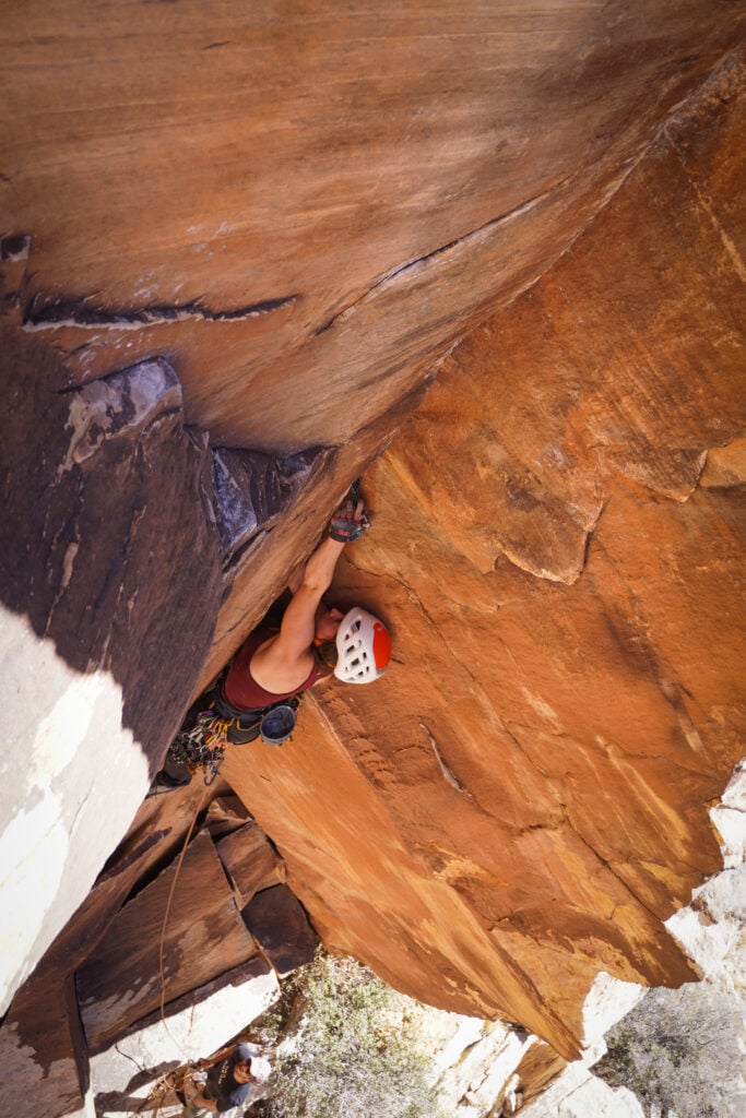 A climber reaches high in a dihedral on an American Alpine Institute rock climbing course in Red Rocks, NV