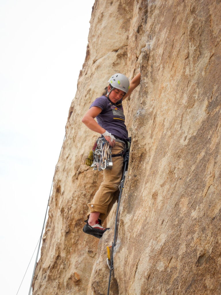 A rock climber in Joshua Tree, CA selects their next piece of gear on an American Alpine Institute rock climbing course