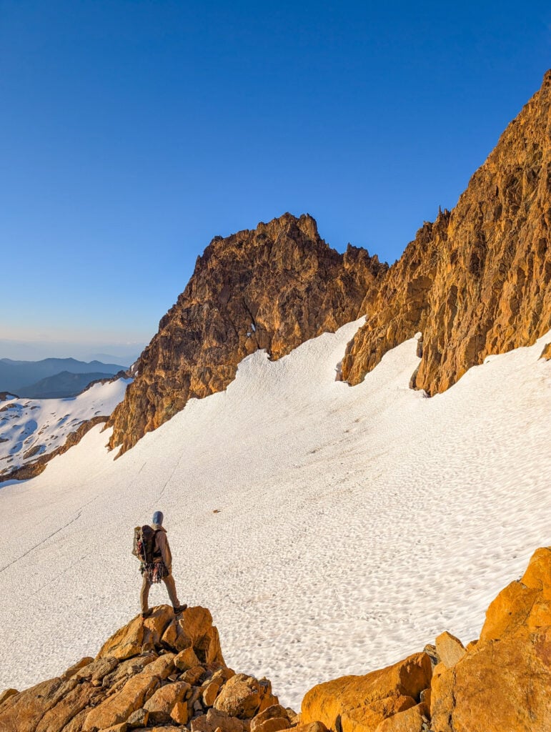 A climber looks on at the vast glacier and rock peaks in the distance during their AMTL 3 program with the American Alpine Institute in the Twin Sisters range of Washington.