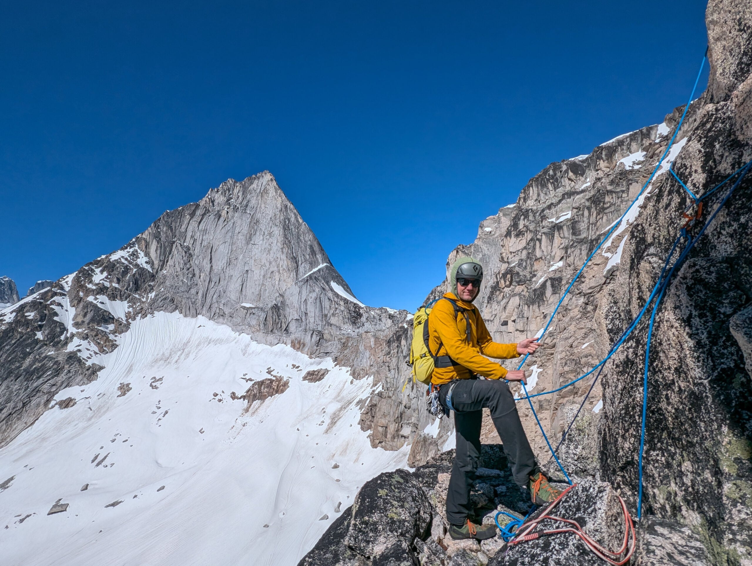 A climber poses at a belay anchor in the Bugaboos of British Columbia on an American Alpine Institute mountaineering course
