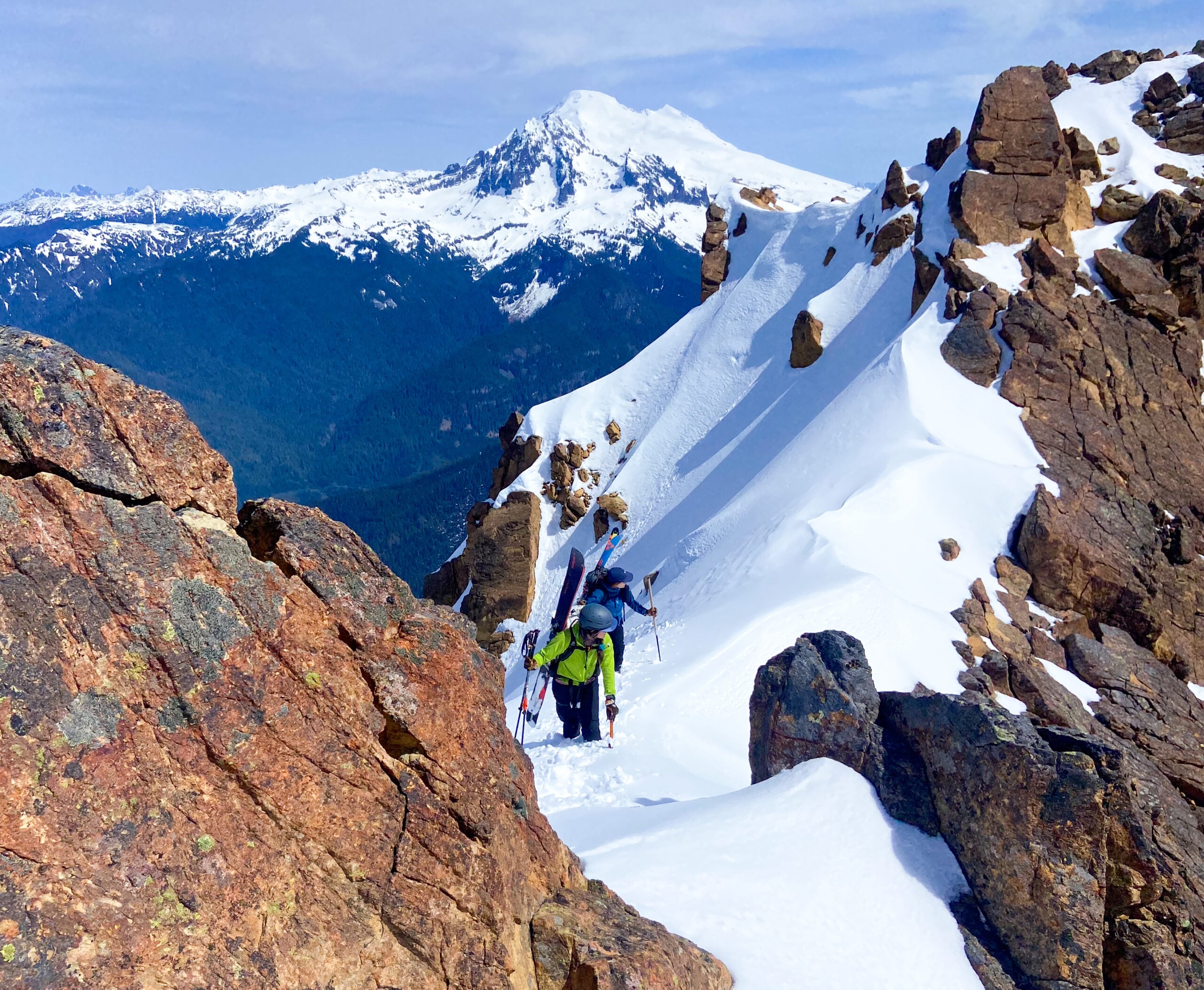 Mt. Baker looms in the background as 2 skiers ascend a slope during an American Alpine Institute Ski course