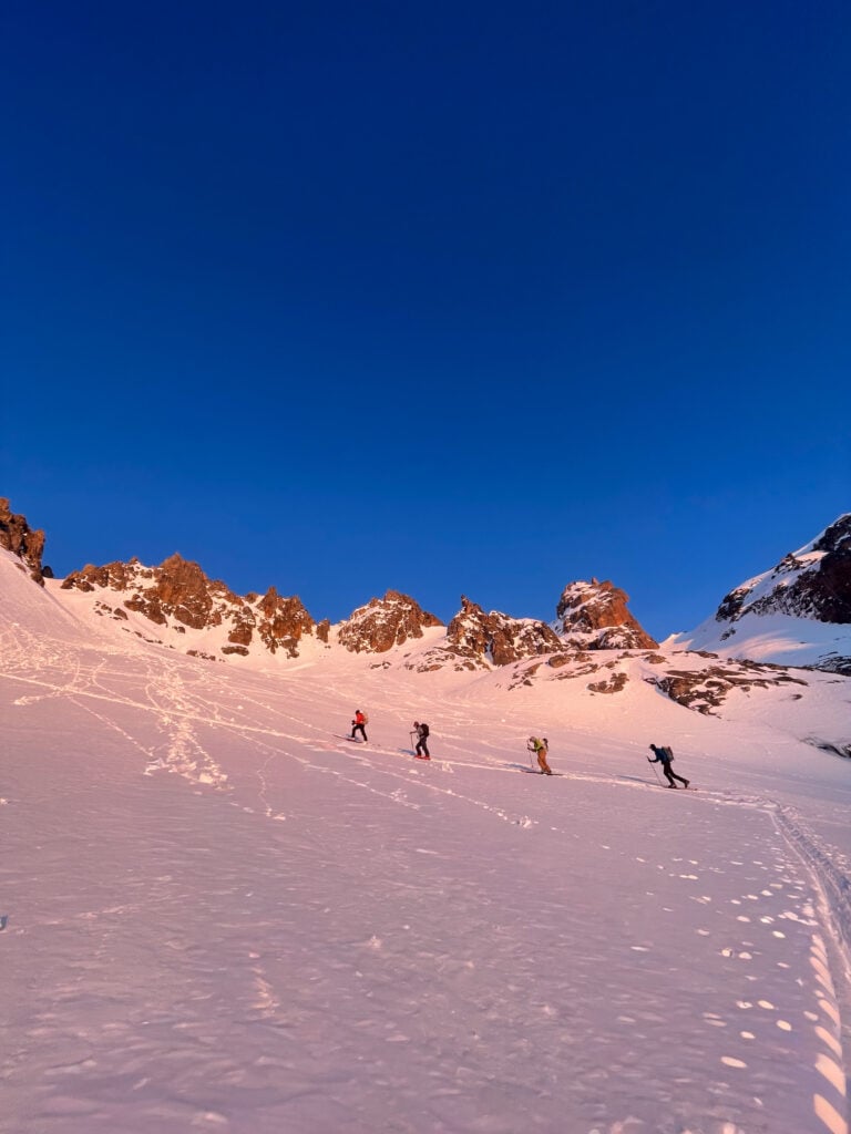 Skiers ascend just as the sun rises setting their skin track to reach the peak as snow conditions ripen during an American Alpine Institute Ski course