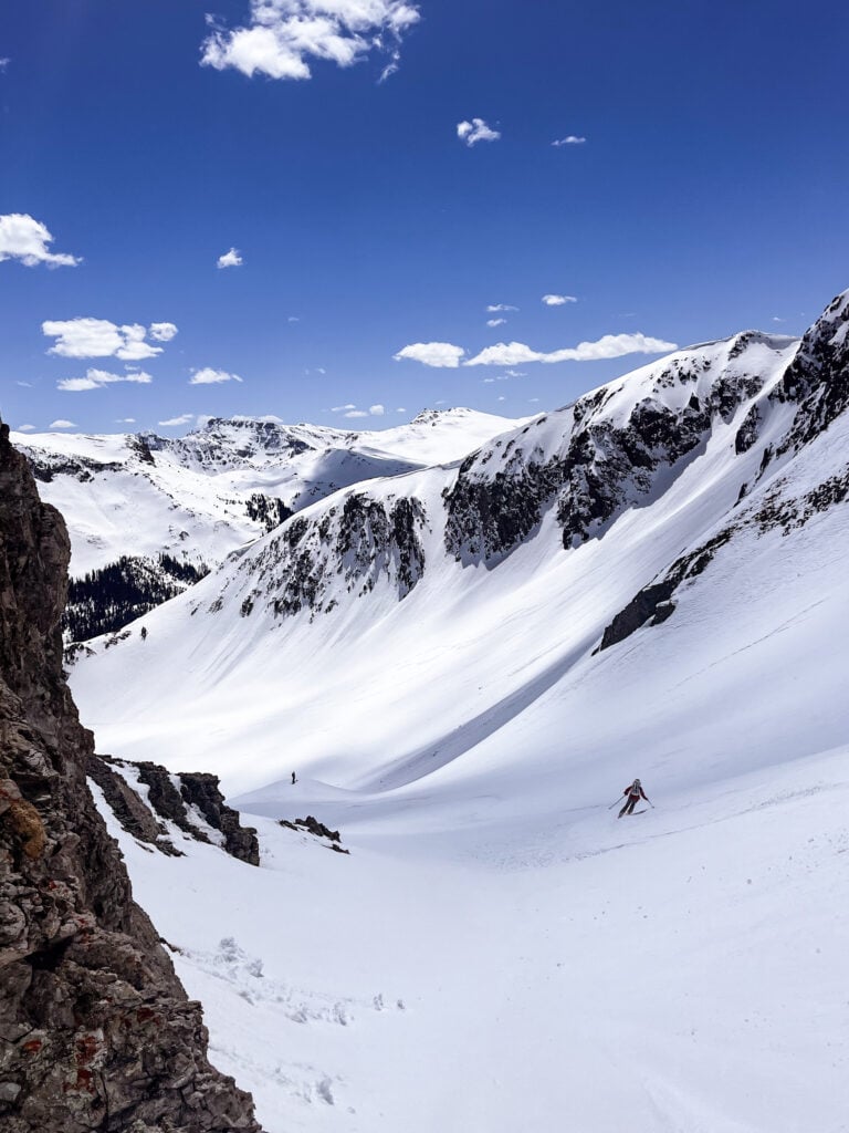 A skier descends a slope in a remote alpine mountain environment in American Alpine Institute Ski courses