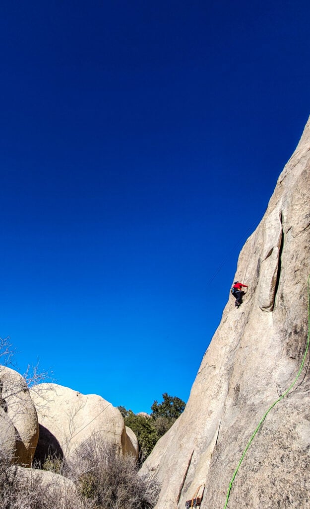 A climber ascends into the blue in Bishop, CA on an American Alpine Institute rock climbing program