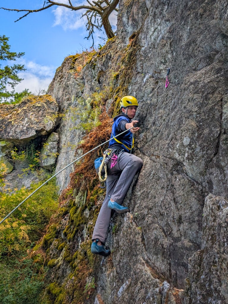 Reaching for the next clip while sport lead climbing during and American Alpine Institute Leaders of Tomorrow Rock Climbing Camp