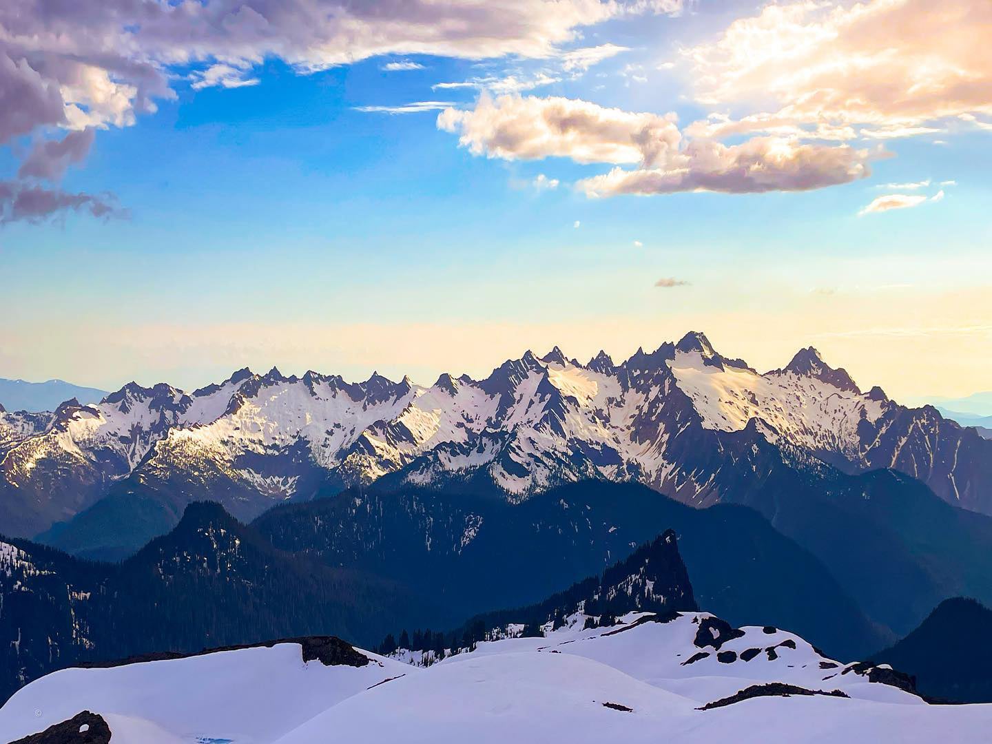 A mountain range glows in the background of camp at sunset. One of many amazing views in the North Cascades during an American Alpine Institute backpacking course