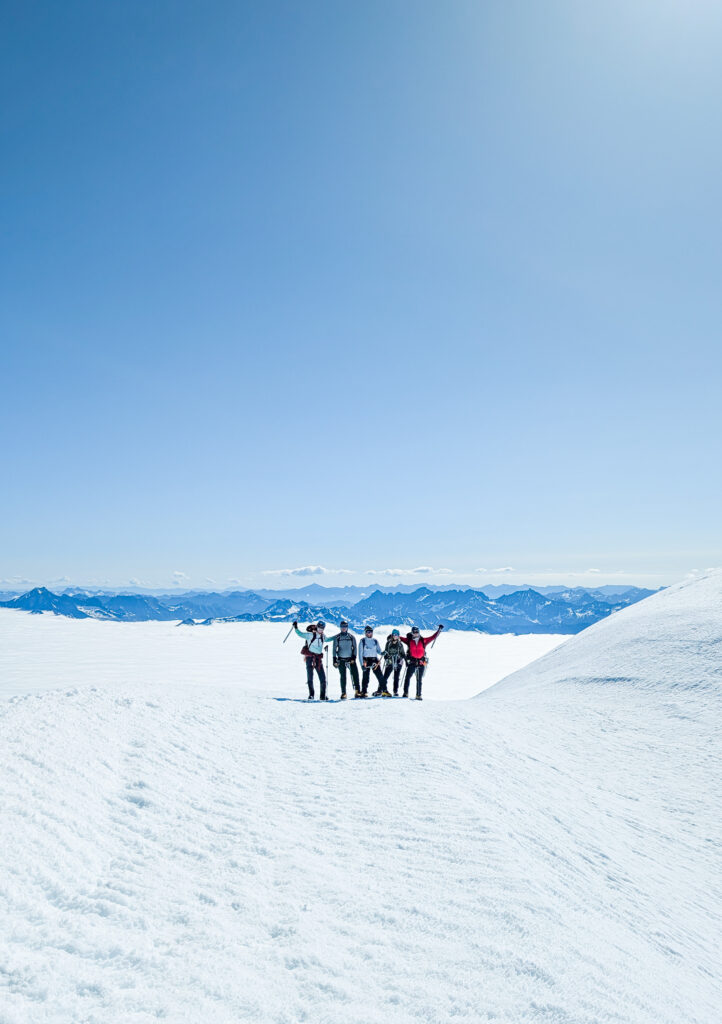 Climbers raise their ice axes on a successful summit of Glacier Peak during their American Alpine Institute mountaineering course
