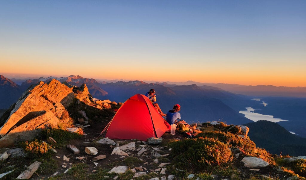 Campers sit at their alpine camp enjoying their meal and each other in a scenic backcountry campsite during an American Alpine Institute course in the North Cascades