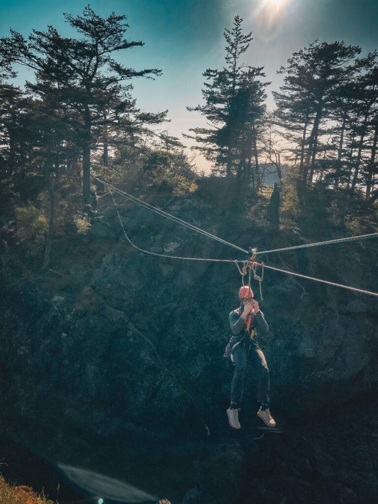 A student hangs between sea cliffs on a complex rope rescue system taught in the American Alpine Institute rope rescue course