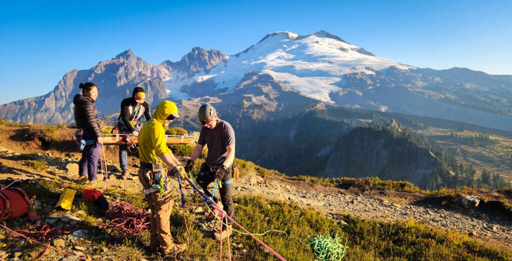 A group of rescuers set up an advanced rope system for a technical rope rescue on Mt. Baker during an American Alpine Institute rope rescue course