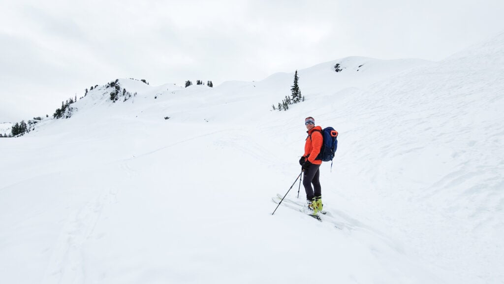A skier takes a moment to smile as they approach the top of their backcountry tour on an American Alpine Institute Ski program in the Mt. Baker Backcountry