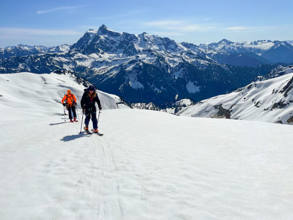 Skiers skin up a slope in the Mt. Baker backcountry with Mt. Shuksan in the background during an American Alpine Institute ski program