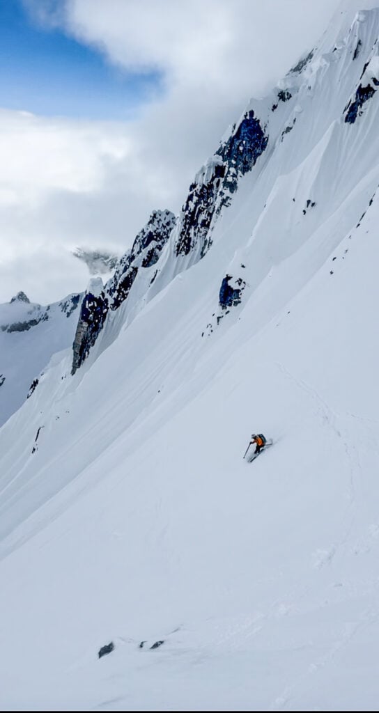 A skier descends a slope after gaining the peak while ski mountaineering with the American Alpine Institute