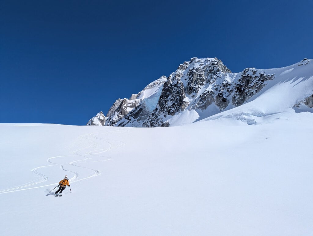 A skier descends a creamy slope in the mountains on an American Alpine Institute ski course